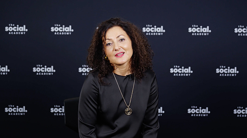 Porträt einer lächelnden Frau vor einer Social-Academy-Hintergrundwand