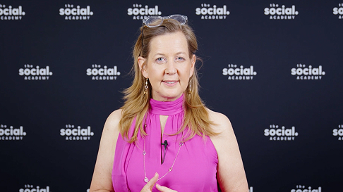 Frau in pinkem ärmellosem Oberteil vor einer Social-Academy-Rückwand