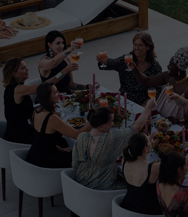 Mehrere Frauen stoßen bei einem Essen mit Cocktails an