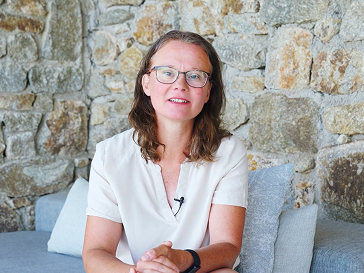 Porträt einer Frau mit Brille, die vor einer Steinwand sitzt