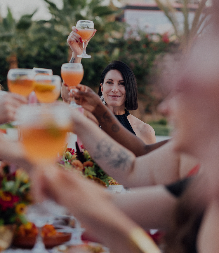Eine Frau hebt bei einem gemeinsamen Essen ein Glas zum Anstoßen